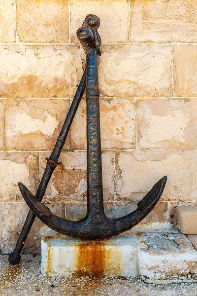 Italy-Apulia-Metropolitan City of Bari-Giovinazzo Old rusted anchor in front of a stone wall